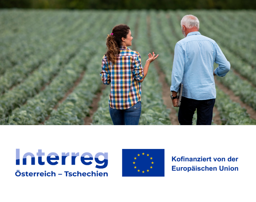 Mann und Frau diskutieren stehend in einem Feld. Darunter ist das Interreg-Logo zu sehen.