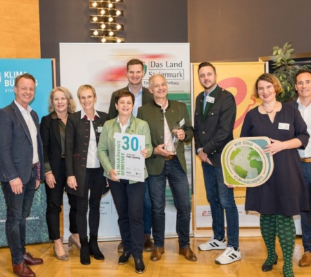 Klimabündnis Auszeichnungsgala: Gemeindevertreter stehen mit Vorständen vor dem Klimabündnis und Land Steiermark Rollup und lächeln. Sie halten die Auszeichnungen in den Händen.