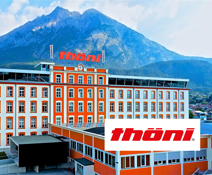 Gebäude der Thöni-Gruppe vor Bergkulisse mit Firmenlogo