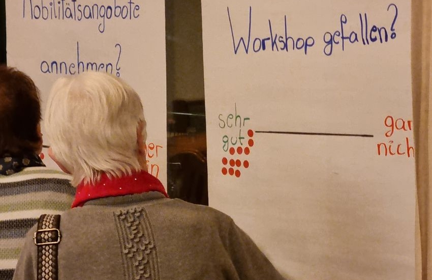 ältere Frau schaut auf Mitmach-Plakat des Workshops