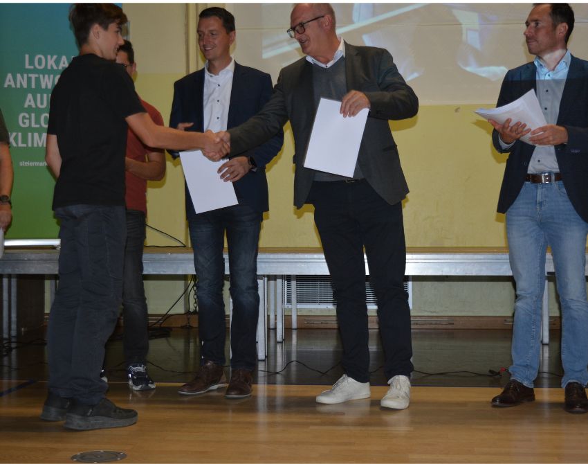 Bürgermeister überreichen einem Schüler eine Urkunde