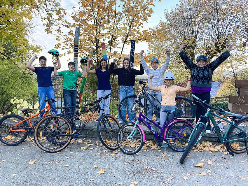 Jubelnde Schüler und Schülerinnen mit Helmen vor ihren Rädern